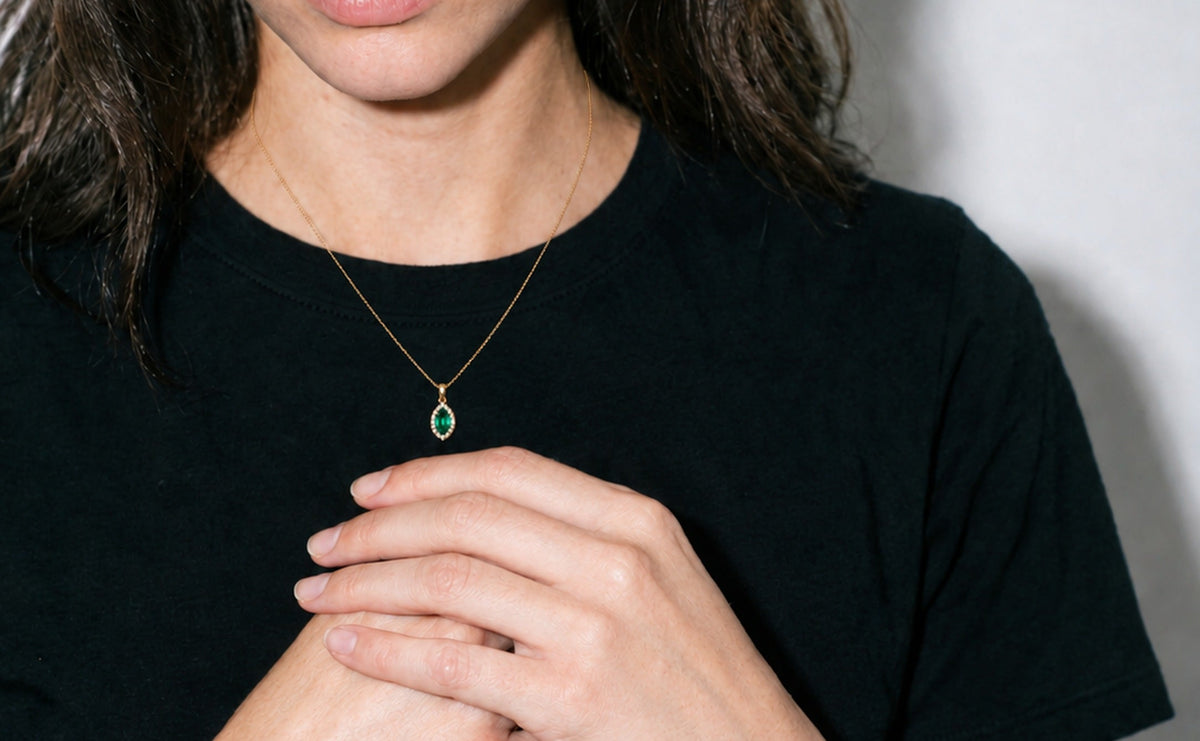Collier Ocelle porté, t-shirt noir, pendentif émeraude marquise et halo de diamants, or jaune