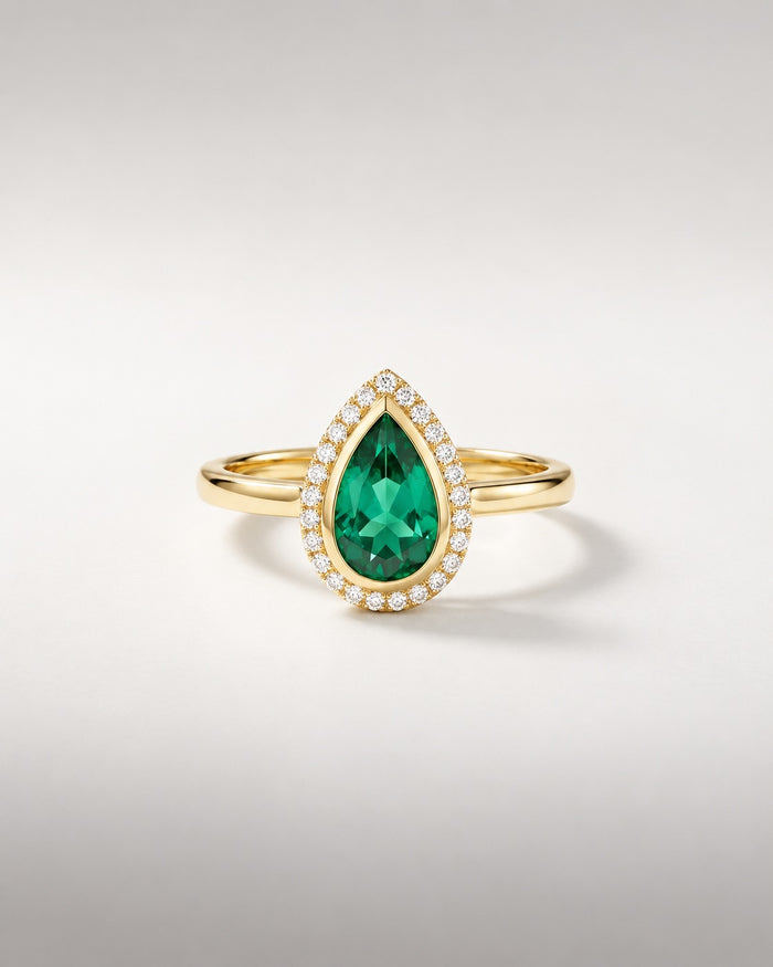 Bague Ocelle — émeraude poire créée en laboratoire en serti clos, halo de diamants, or jaune — vue de face