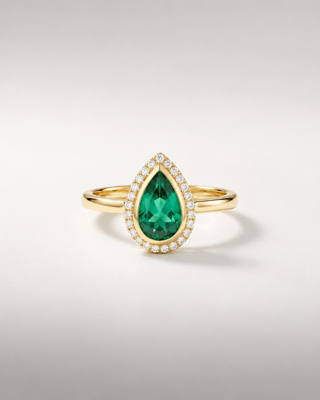 Bague Ocelle — émeraude poire créée en laboratoire en serti clos, halo de diamants, or jaune — vue de face