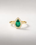 Bague Ocelle — émeraude poire créée en laboratoire en serti clos, halo de diamants, or jaune — vue de face