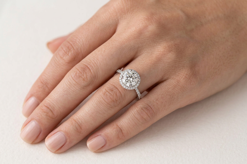 Bague Halo portée à l'annulaire — diamant rond, halo et épaules pavées, or blanc — Carron Olivier