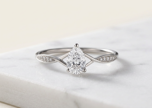 Bague Infini, diamant taille poire sur anneau croisé pavé, or blanc, sur marbre blanc — Carron Olivier