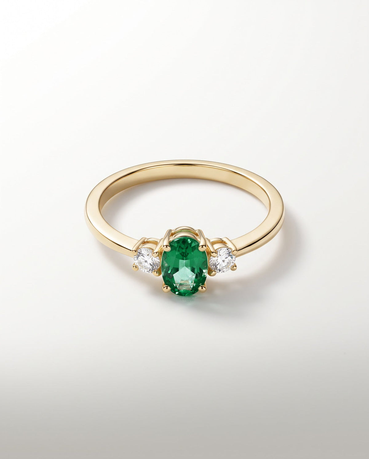 Bague Trilogie, émeraude ovale vert profond et deux diamants, or jaune — packshot